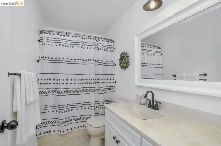 White bathroom featuring a single vanity with an integrated sink, a light-toned countertop, and a matte black faucet