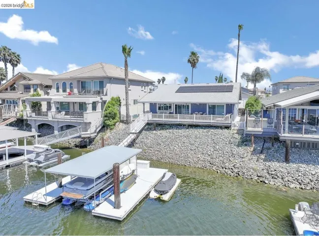 Waterfront property featuring a private boat dock with covered slip, solar panels, and a spacious deck