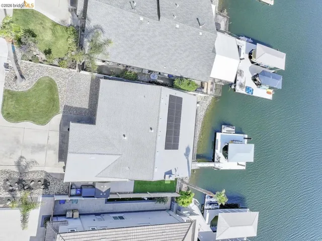 Waterfront property with a gray shingle roof and solar panel array