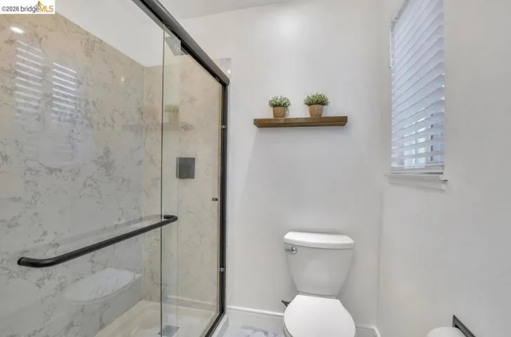 Shower enclosure featuring a black-framed glass door, white marbled tile surround, and matte black shower fixtures