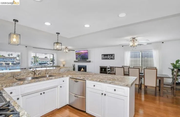 White cabinetry with black hardware, stone-finish countertops, stainless steel appliances, and a double basin sink