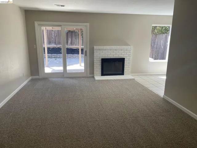Living area featuring a white brick fireplace, sliding glass door, and neutral-toned carpeting