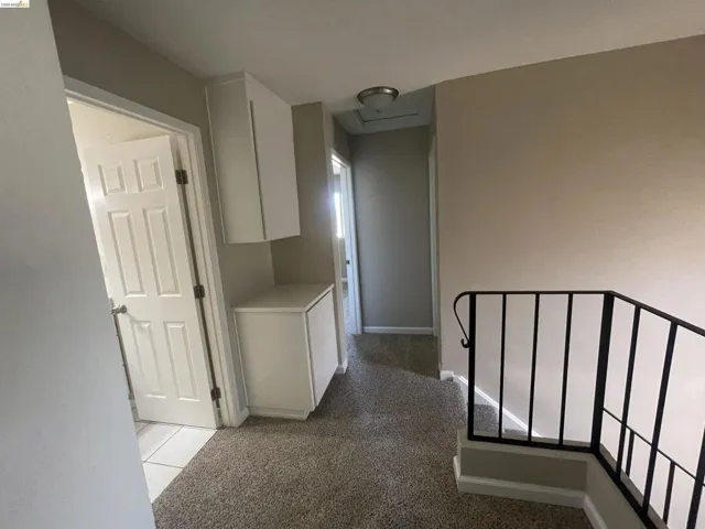 Hallway featuring neutral-toned walls, built-in white cabinetry, and carpeted flooring