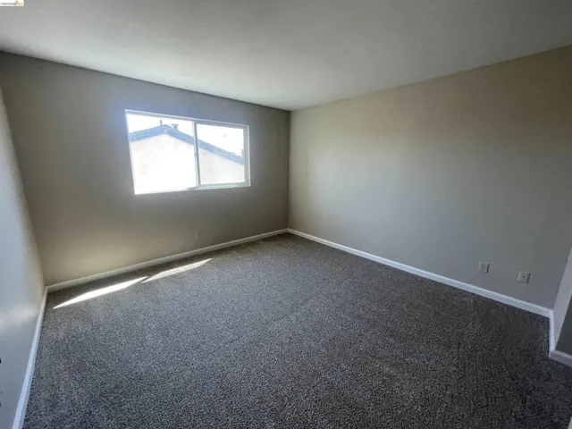 Room featuring neutral-toned walls, a white ceiling, and grey speckled carpeting