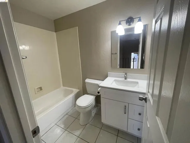 Bathroom featuring a white vanity with an integrated sink, polished chrome faucet, and a wall-mounted mirror with a two-light fixture