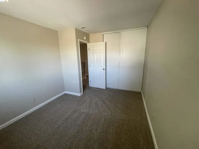 Carpeted room featuring neutral wall tones, white trim, a solid door, and a sliding door closet