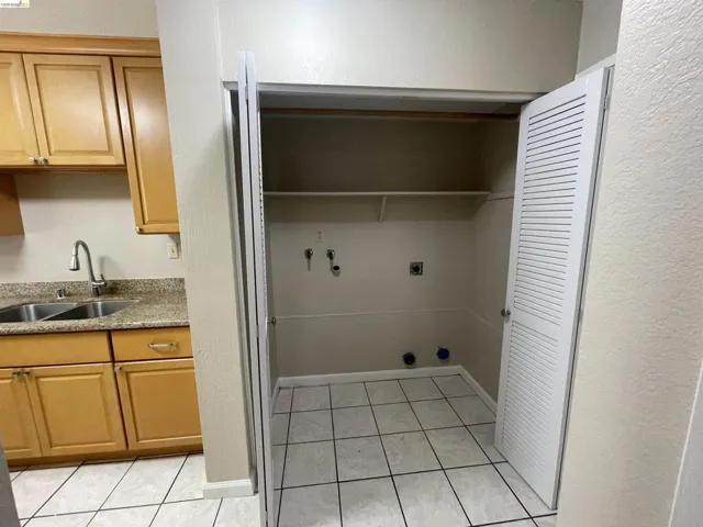 Utility closet with louvered bi-fold doors, tile flooring, and integrated shelving