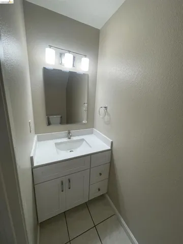 Vanity with an integrated sink and white countertop, featuring white shaker-style cabinetry, chrome hardware, and a framed mirror