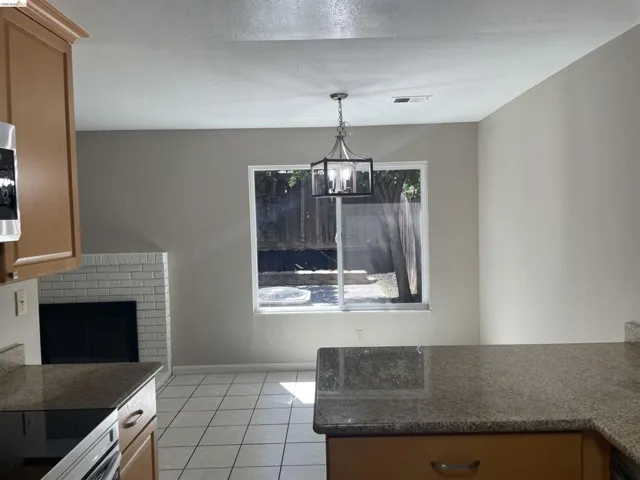 Dining area with tile flooring and a fireplace featuring white brick surround