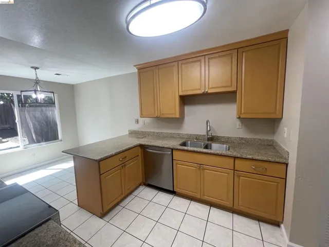 Kitchen featuring light wood-finish cabinetry, speckled countertops, and a dual stainless steel sink