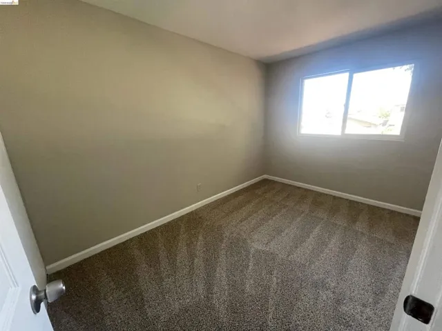 Room with neutral-toned walls and plush, speckled carpeting