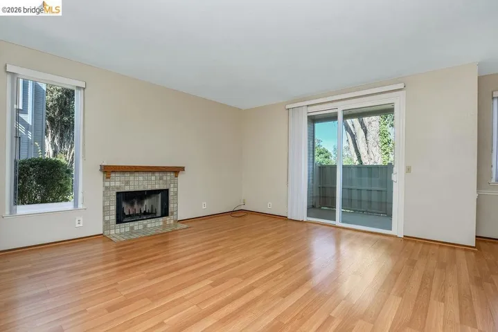 Living area featuring wood-finish flooring, a tile-surround fireplace with a wood mantle, and sliding glass doors opening to an exterior space