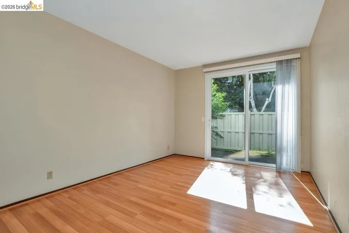 Wood-finish flooring throughout, featuring a sliding glass door with sheer curtain