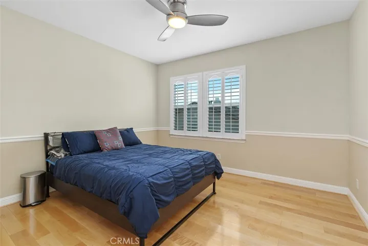 Upstairs bedroom with ceiling fan and shutters
