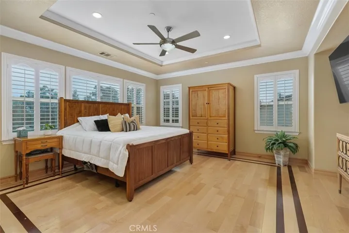 Primary bedroom with ceiling fan and shutters