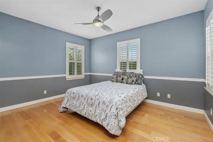 Upstairs bedroom with ceiling fan and shutters