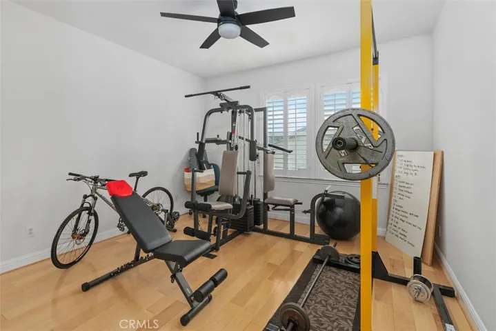 Upstairs bedroom with ceiling fan and shutters currently used as a home gym