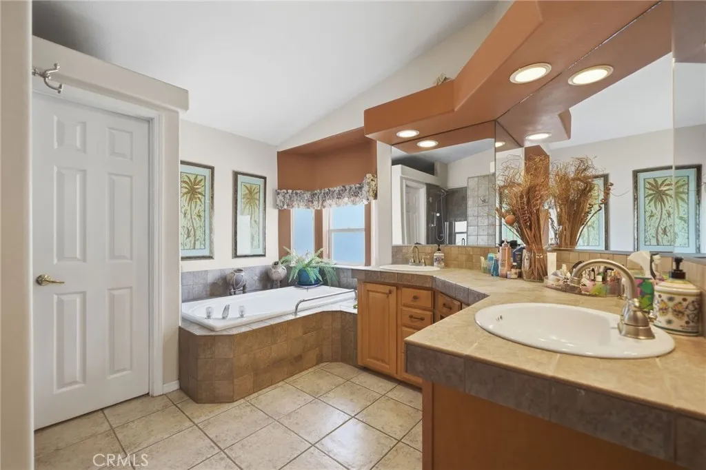 Primary bathroom w dual sinks, stone tile countertops and separate tub and shower