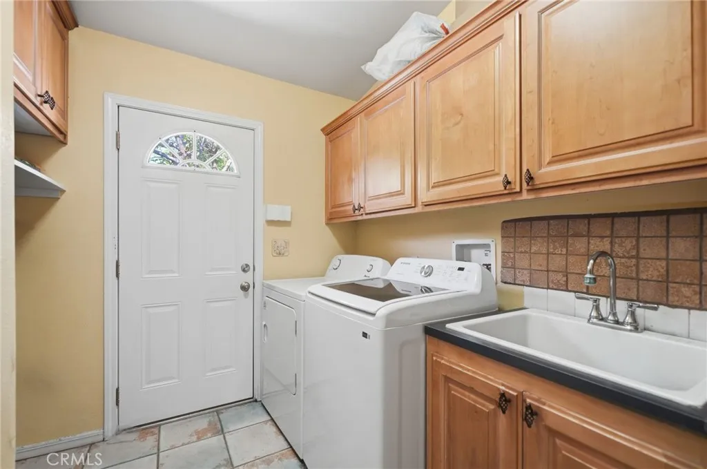 Laundry room w plenty of cabinet storage, sink and doorway to exterior.