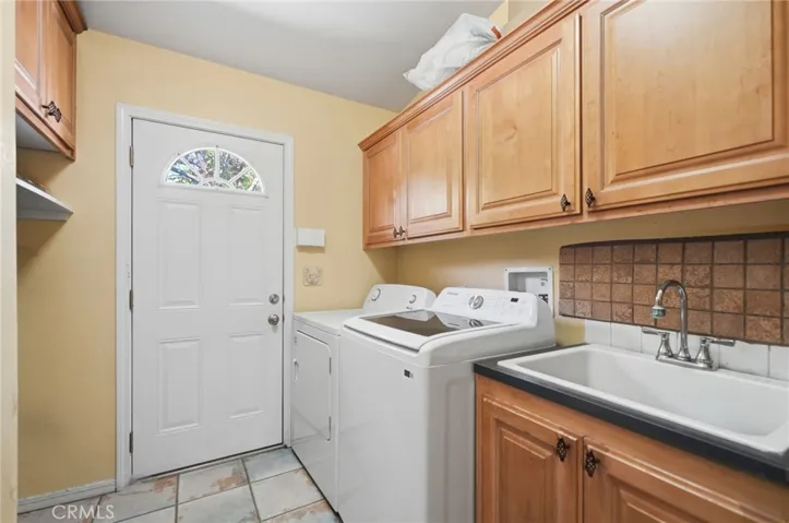 Laundry room w plenty of cabinet storage, sink and doorway to exterior.