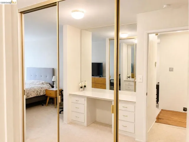 Mirrored sliding closet doors with brass-tone frames, integrated vanity with white countertop, built-in drawers, and recessed lighting