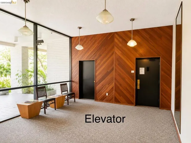 Lobby area featuring full-height exterior windows, herringbone wood wall paneling, and two pendant light fixtures