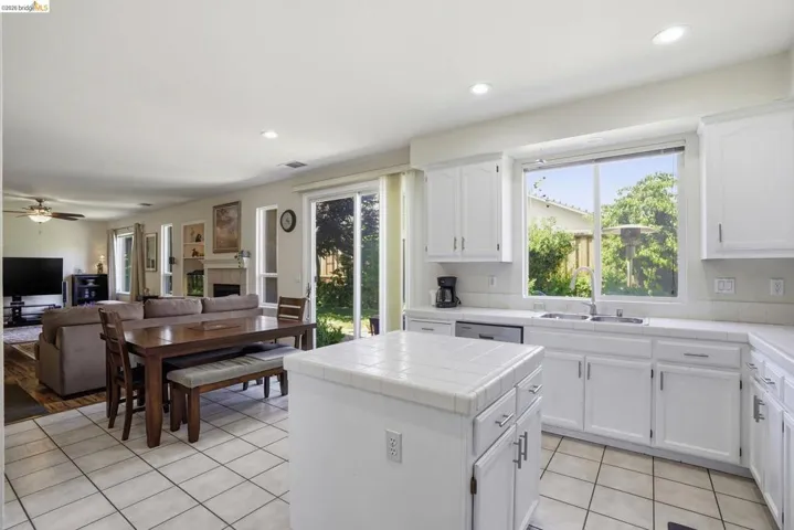 Kitchen featuring white cabinetry, tile countertops, recessed lighting, and a stainless steel dishwasher