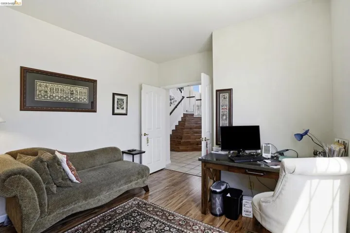 Room featuring wood-finish flooring, white walls, and a visible doorway leading to a staircase with wood treads and white risers