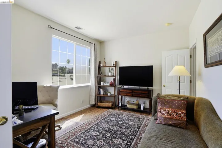 Large window with grid patterns, wood-finish flooring, white walls, and a white interior door with a brass-finish knob