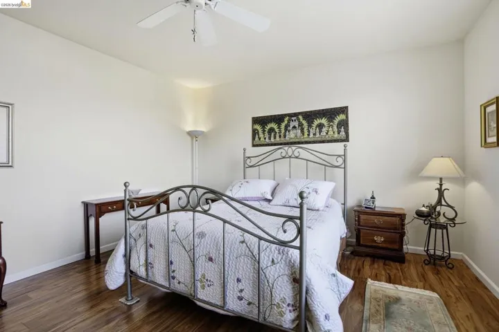 Spacious room featuring wood-finish flooring, light-toned walls, and a ceiling fan