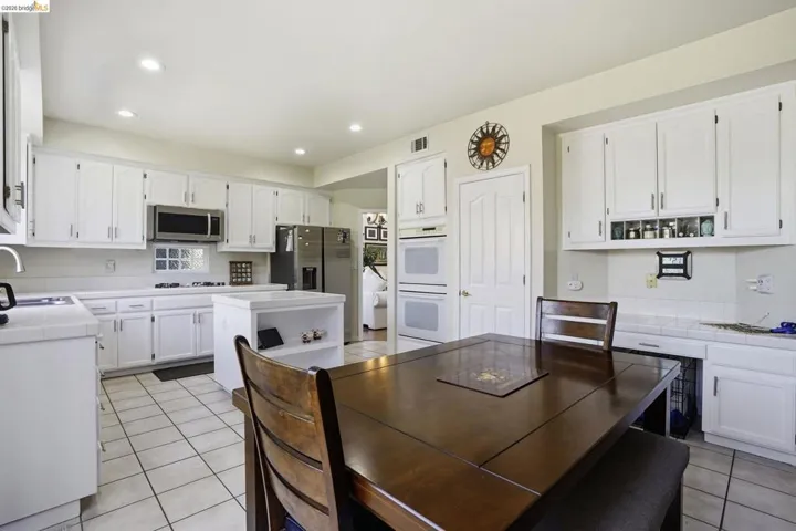Kitchen featuring white cabinetry, tile countertops, stainless steel appliances, and recessed lighting