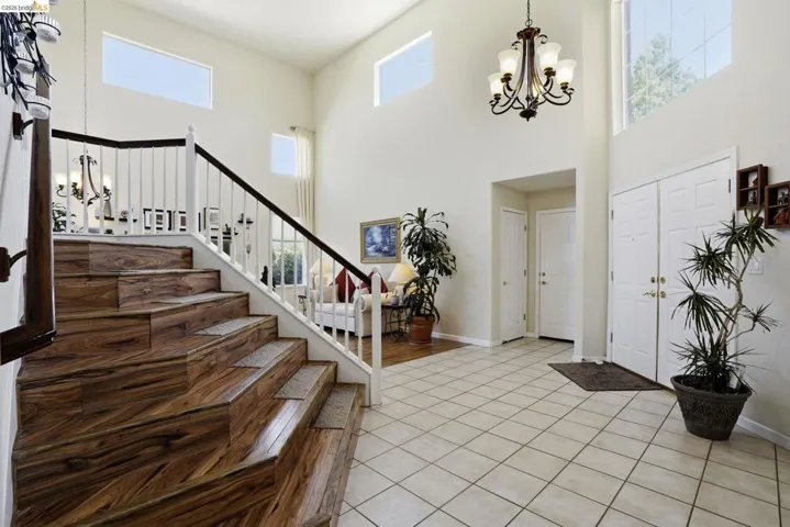 Grand entry foyer featuring a double-height ceiling, ceramic tile flooring, and a decorative chandelier
