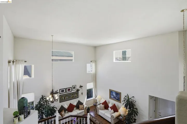 Voluminous two-story interior featuring multiple upper-level windows, a suspended chandelier, and hardwood flooring