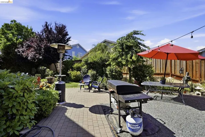Paved patio area featuring lush perimeter landscaping and a gravel section