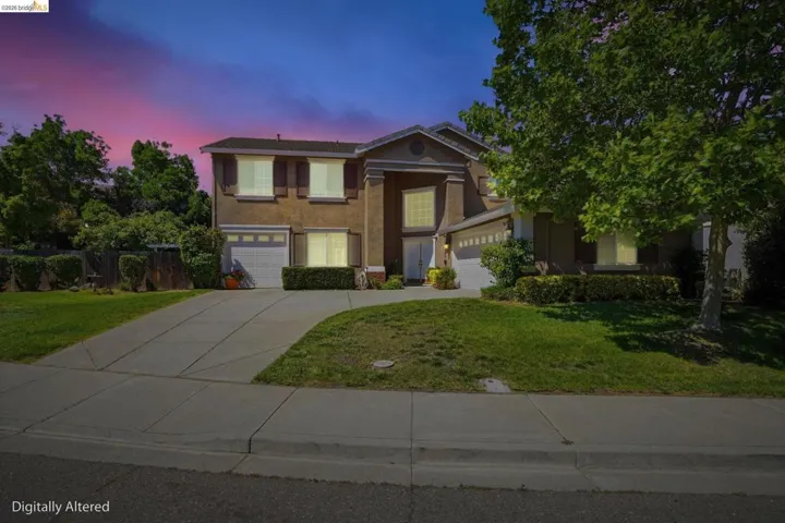 Two-story property featuring a stucco exterior, multiple front-facing windows with shutters, and an attached two-car garage