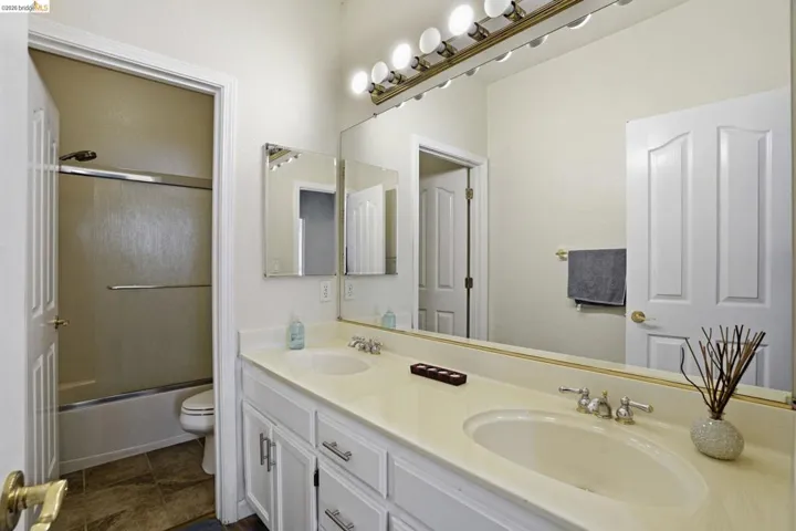 Double vanity with integrated sinks, white cabinetry, and brushed nickel hardware