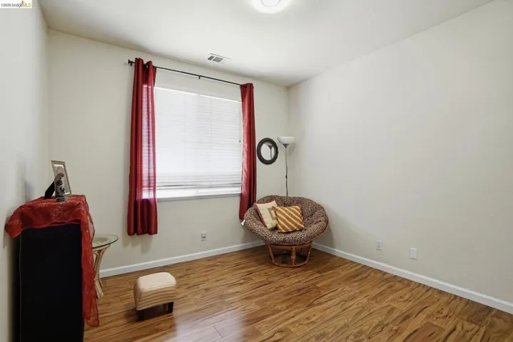 Room featuring wood-finish flooring, a window with blinds, and white baseboards