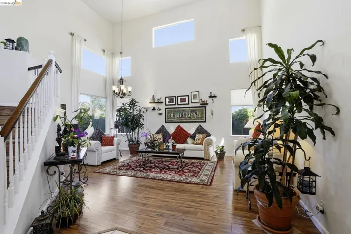 Two-story foyer featuring wood-finish flooring and a white baluster staircase with a dark wood handrail