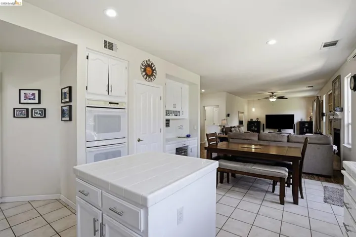 Kitchen island with a tiled countertop and white cabinetry, complemented by a built-in double oven