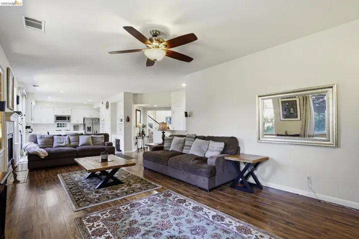 Expansive open-concept living area featuring wood-finish flooring, a ceiling fan with integrated lighting, and recessed lighting