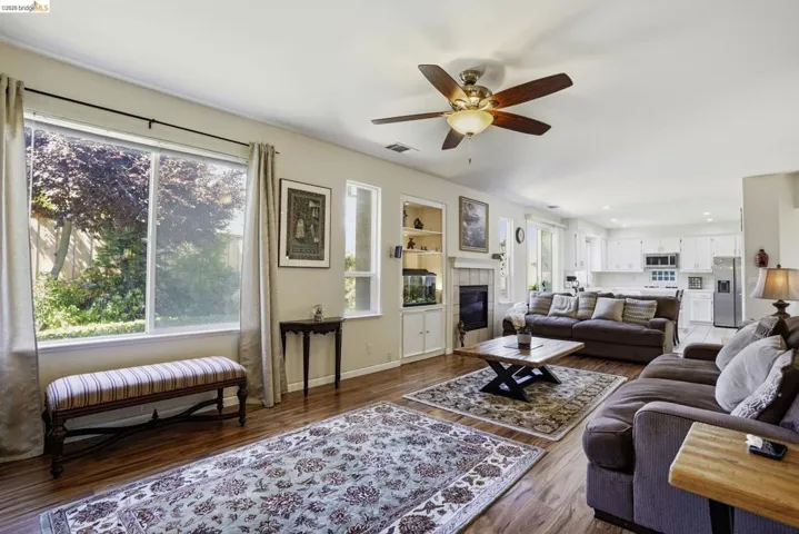 Open-concept living space featuring wood-finish flooring, a ceiling fan, and built-in shelving