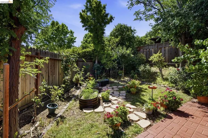 Private backyard featuring a paver patio, flagstone path, mature trees, and raised garden beds
