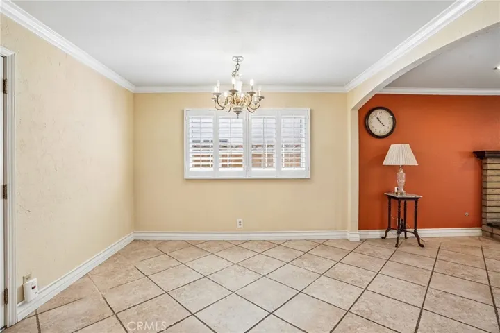 Dining Area- The inviting dining area flows seamlessly into the kitchen, creating a warm and functional space perfect for everyday living and entertaining. The kitchen features rich wood cabinetry, ample storage, tile flooring, and a convenient breakfast bar opening to the adjacent living spaces. Natural light pours through plantation shutters, while the dining area offers an elegant chandelier and comfortable setting for gatherings with family and friends. The open layout provides both charm and practic...