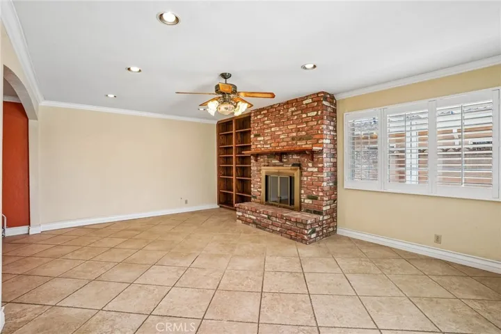Bonus Room - This spacious bonus room offers the perfect blend of comfort and character, featuring a stunning floor-to-ceiling brick fireplace, custom built-in shelving, and an open layout ideal for entertaining or relaxing. Large windows and sliding glass doors bring in abundant natural light and provide seamless access to the backyard and pool area. With recessed lighting, tile flooring, and versatile living space, this room is ideal as a family room, game room, media space, or oversized lounge area.