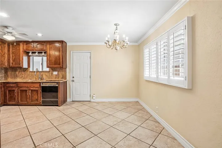 Dining Area- The inviting dining area flows seamlessly into the kitchen, creating a warm and functional space perfect for everyday living and entertaining. The kitchen features rich wood cabinetry, ample storage, tile flooring, and a convenient breakfast bar opening to the adjacent living spaces. Natural light pours through plantation shutters, while the dining area offers an elegant chandelier and comfortable setting for gatherings with family and friends. The open layout provides both charm and practic...