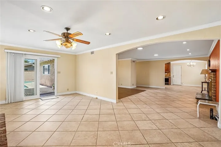 Bonus Room - This spacious bonus room offers the perfect blend of comfort and character, featuring a stunning floor-to-ceiling brick fireplace, custom built-in shelving, and an open layout ideal for entertaining or relaxing. Large windows and sliding glass doors bring in abundant natural light and provide seamless access to the backyard and pool area. With recessed lighting, tile flooring, and versatile living space, this room is ideal as a family room, game room, media space, or oversized lounge area.