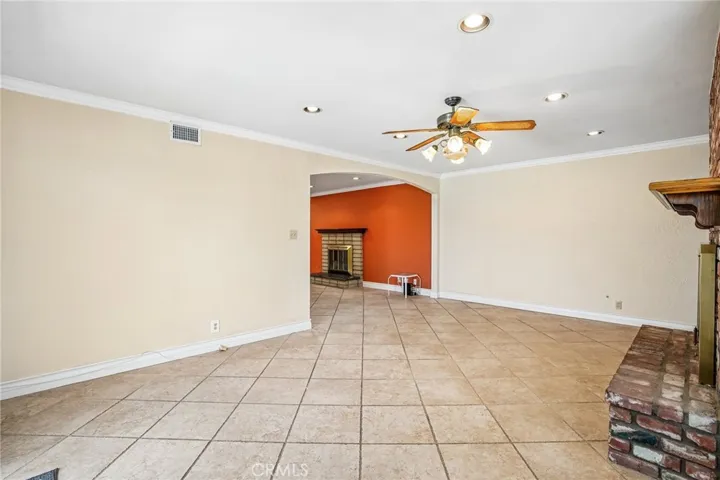 Bonus Room - This spacious bonus room offers the perfect blend of comfort and character, featuring a stunning floor-to-ceiling brick fireplace, custom built-in shelving, and an open layout ideal for entertaining or relaxing. Large windows and sliding glass doors bring in abundant natural light and provide seamless access to the backyard and pool area. With recessed lighting, tile flooring, and versatile living space, this room is ideal as a family room, game room, media space, or oversized lounge area.