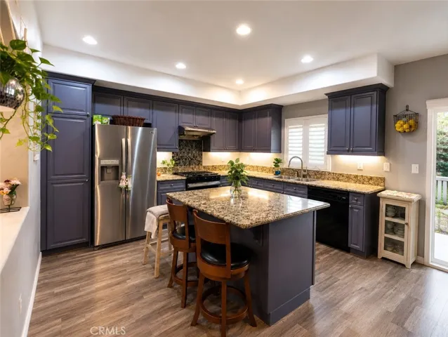 The gourmet kitchen is a true centerpiece, featuring granite countertops, extensive cabinetry with contemporary painted finishes, and a large center island