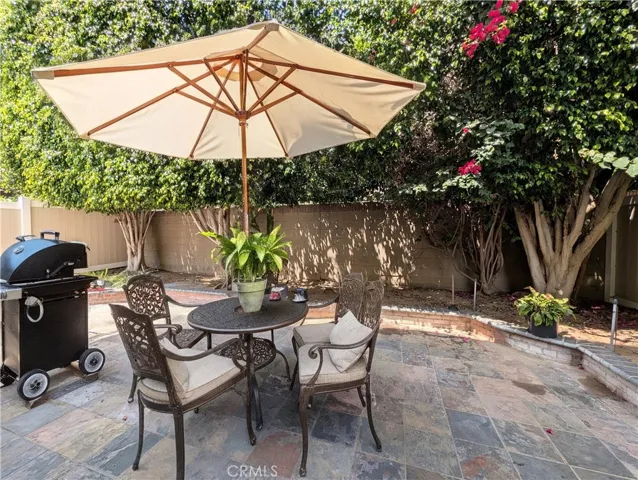Entertaining Backyard with Slate patio and lush trees. This image has been virtually staged to illustrate the potential use of space. Furnishings, finishes, and décor shown may not exist in the home and are not included in the sale.)
