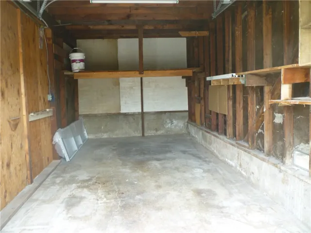 Interior of the private one-car garage assigned to unit #1 with a storage shelf at the front.